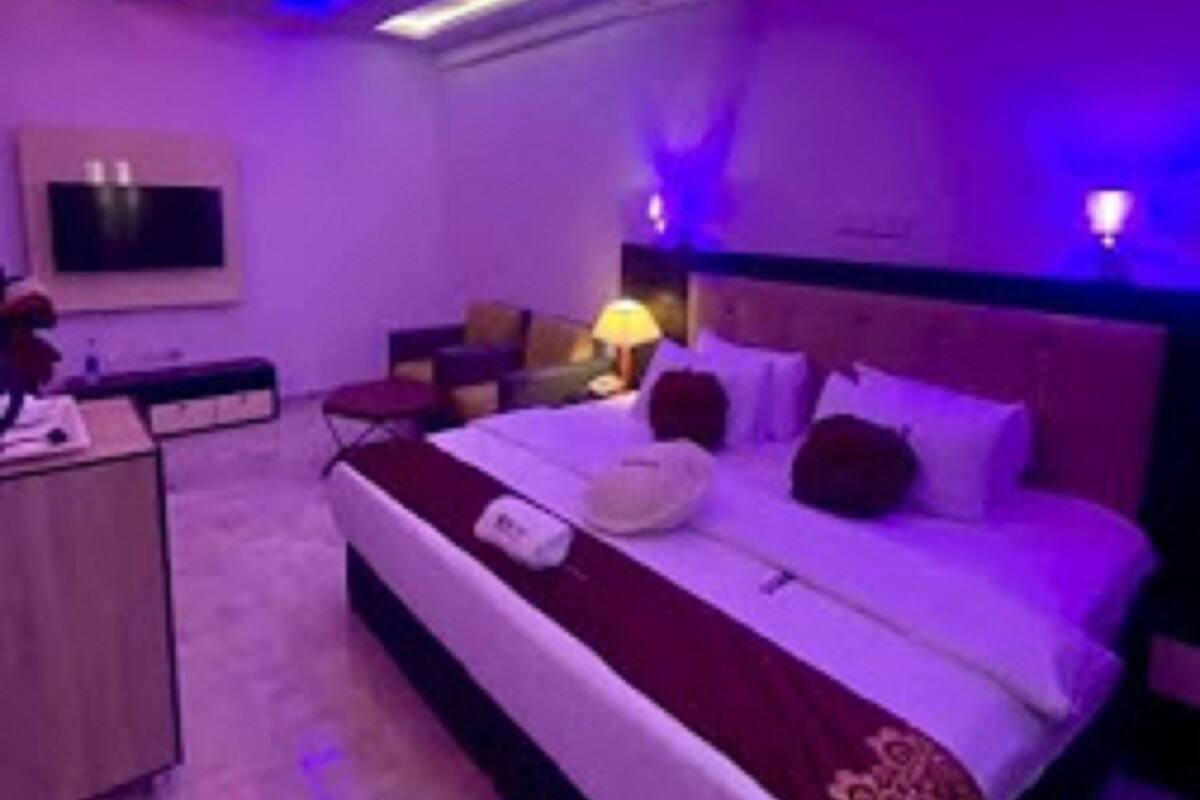 A modern hotel room with a large bed, bedside tables, a desk, and a TV.