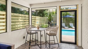 Une terrasse avec une table et des chaises, une piscine et une clôture en bois.