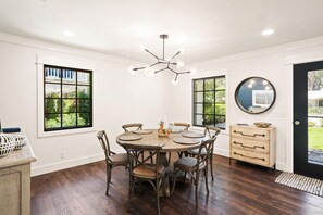 A dining area with a round table, chairs, and a chandelier.