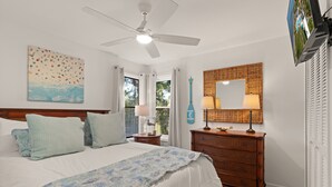 Ein Schlafzimmer mit einem Bett, einem Deckenventilator, einem Schminktisch, einem Spiegel und einem Bild an der Wand.