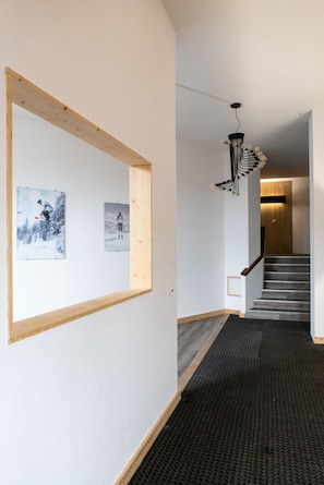 A hallway with a wooden frame on the wall, a black textured floor, and a staircase leading to another room.