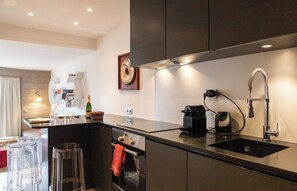 A modern kitchen with a built-in oven, a coffee maker, and a sink.