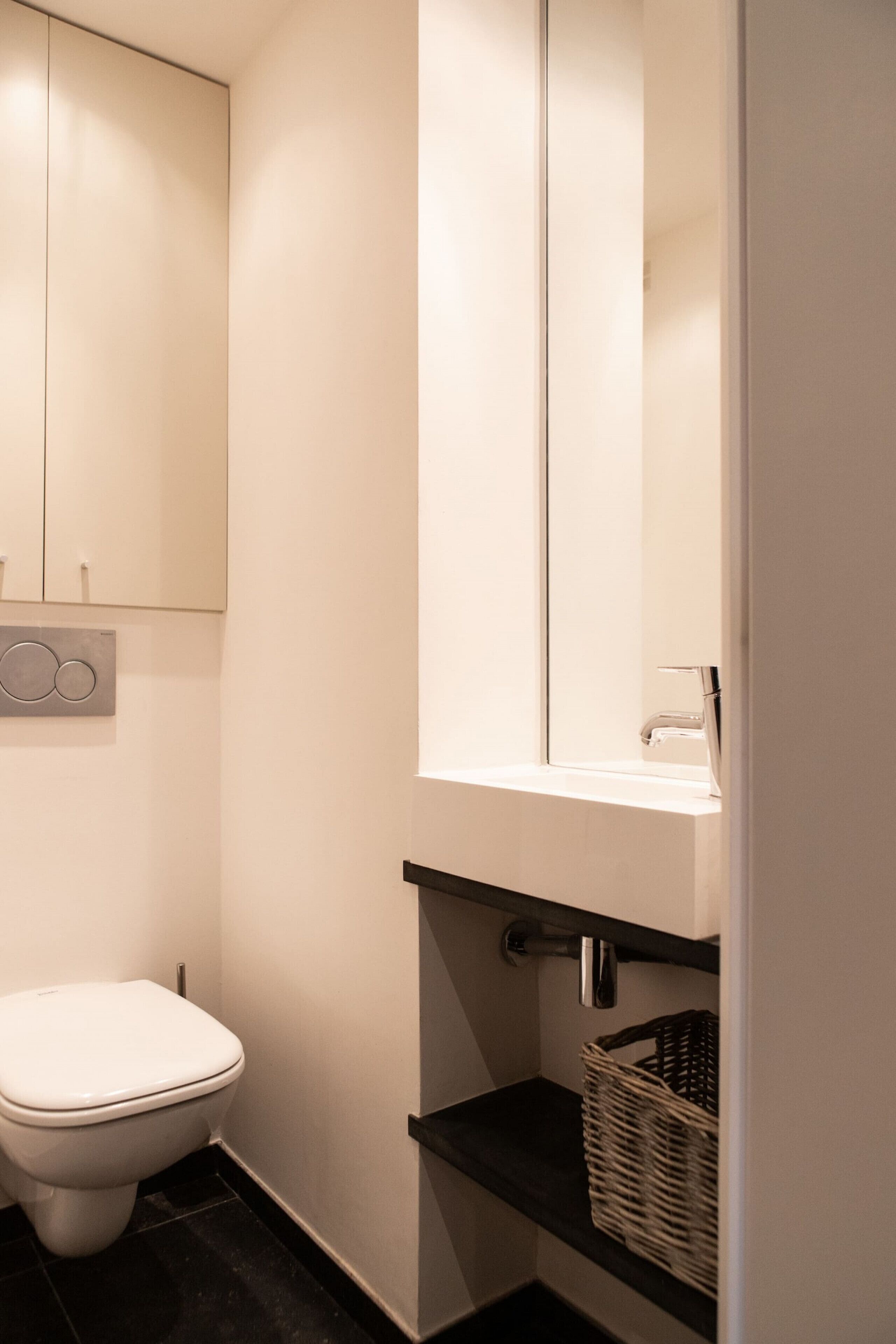 Et moderne badeværelse med toilet, håndvask og spejl.