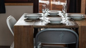 Comedor con una mesa dispuesta para cuatro, vista de un paisaje nevado a través de una ventana y una lámpara a la derecha.