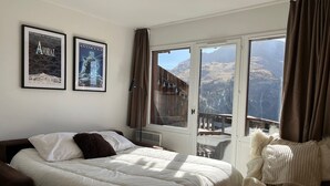 A bedroom with a bed, a chair, and a large window with a mountain view. - Immodreams - Le Dahu - Avoriaz (Avoriaz)