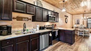 Una cocina moderna con armarios de madera oscura, electrodomésticos de acero inoxidable y techo de madera.
