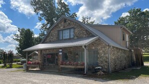 A stone building with a metal roof, a porch with outdoor seating, and a sign that reads "FIREWORKS".