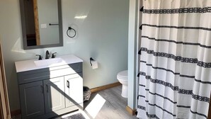 A bathroom with a sink, mirror, toilet, and shower curtain.