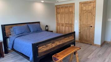 A bedroom with a wooden bed frame, a bench, and two wooden doors.