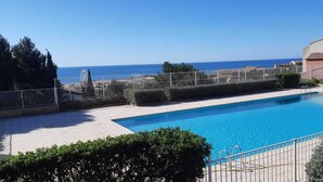 Piscina retangular com água azul cristalina, rodeada por um deck pavimentado.