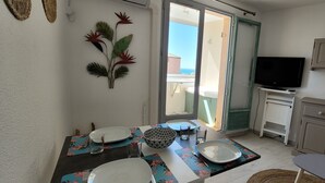 Cozinha compacta com área de refeições, TV e vista para o exterior.