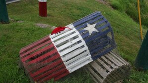 A birdcage with a flag design, placed on grass. - Gaudet Chalets & Motel (Shediac)