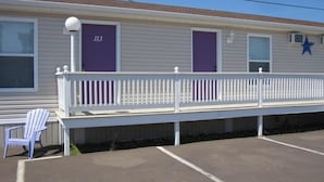 A motel with a white exterior, numbered room 113, and a purple door. - Gaudet Chalets & Motel (Shediac)