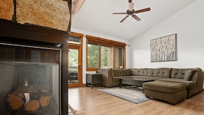 Una sala de estar moderna con un sofá modular, una chimenea y ventanas amplias con vistas al exterior.