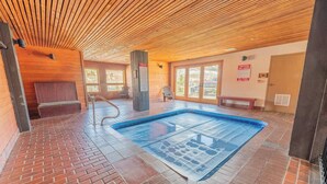 Un'area benessere con piscina, soffitto in legno e pavimento in mattoni.