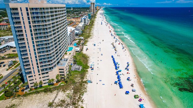 A beachfront hotel with multiple floors, a sandy beach, and ocean views.