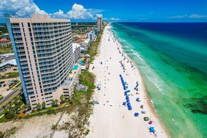 A beachfront hotel with multiple floors, a sandy beach, and ocean views.