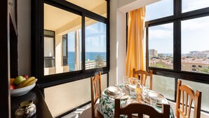 A dining area with a table set for two, overlooking a coastal view. - MalagaSuite Aloha Playa (Benalmádena)