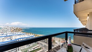 A balcony with a view of the sea, a bottle of wine, and a glass on a table. - MalagaSuite Aloha Playa (Benalmádena)