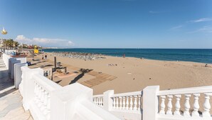 A beach with a white railing, a wooden deck, and a clear blue sky. - MalagaSuite Aloha Playa (Benalmádena)