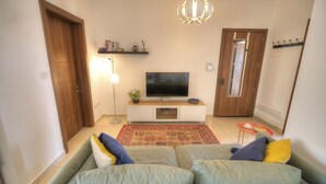 Un salon avec un canapé, un téléviseur et un tapis rouge à motifs.