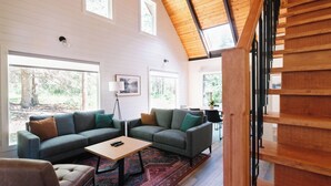 Un salon spacieux avec un haut plafond, de grandes fenêtres et un coin salon confortable.