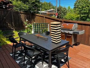 Un patio con mesa y sillas, una parrilla y una cerca decorativa.