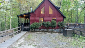 Una baita di legno rossa con veranda in legno e portico coperto, circondata da alberi.