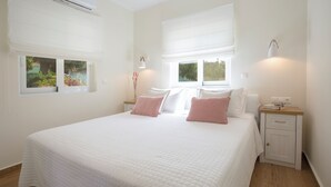 Une chambre à coucher avec un grand lit, deux tables de chevet, une commode et une fenêtre avec des stores.