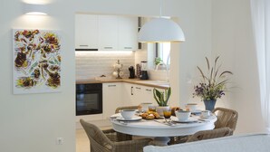 Une cuisine moderne avec des meubles blancs, une table à manger avec des chaises et un luminaire suspendu.