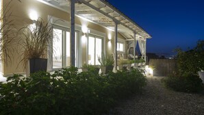 Une maison dotée d’un porche abrité, de plantes en pot et d’un chemin de gravier menant à l’entrée.