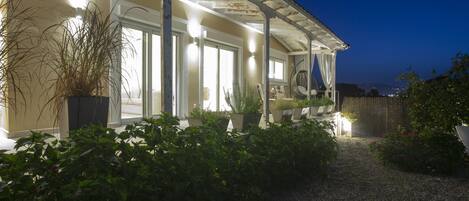 A house with a covered porch, potted plants, and a gravel path leading to the entrance.