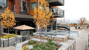 A modern building with a rooftop pool, outdoor seating, and a landscaped garden. - Beautiful unit overlooking Mountain ski in ski out luxury property (Breckenridge)