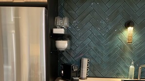 Una cocina moderna con refrigerador de acero inoxidable, armarios de madera, salpicadero con motivo de espiga y una cafetera.