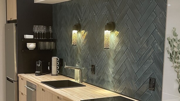 Una cocina moderna con salpicadero de diseño en patrón de espiga, electrodomésticos de acero inoxidable y encimera de madera clara.