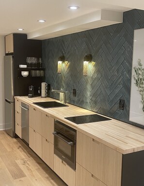 Una cocina moderna con salpicadero de diseño en patrón de espiga, electrodomésticos de acero inoxidable y encimera de madera clara.
