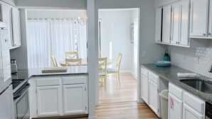 A modern kitchen with white cabinets, a granite countertop, and a stainless steel sink. - Pet Friendly 3 BR Condo across from beach! (Gulf Shores)