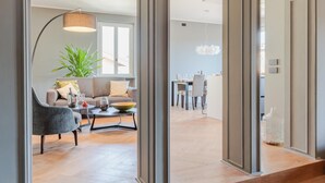 A modern living room with a sofa, coffee table, and a dining area in the background. - Casa Grey Contemporary Penthouse (Lucca)