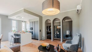 A modern living room with a dining area, kitchen, and a cozy seating area with a fireplace. - Casa Grey Contemporary Penthouse (Lucca)