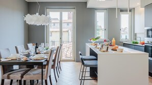 A modern kitchen with a dining area, large windows, and a view of the outside. - Casa Grey Contemporary Penthouse (Lucca)