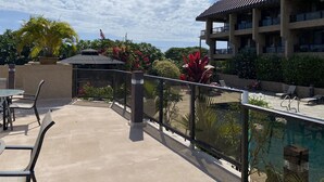 Ein Poolbereich auf dem Dach mit Liegestühlen, einer Glasbrüstung und Blick auf ein Gebäude mit Balkonen.