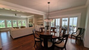 A spacious living room with a large sofa, a dining table with chairs, and a fireplace. - Charming 4b/3b Newly Constructed Home on Dataw Island - Available 5/15 - 10/15 (Dataw Island)