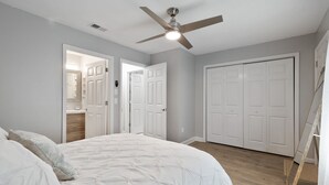 Un dormitorio con cama, ventilador de techo y puertas blancas.