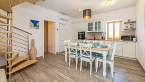 Una cocina moderna con armarios blancos, una mesa de comedor de madera y una escalera en espiral.