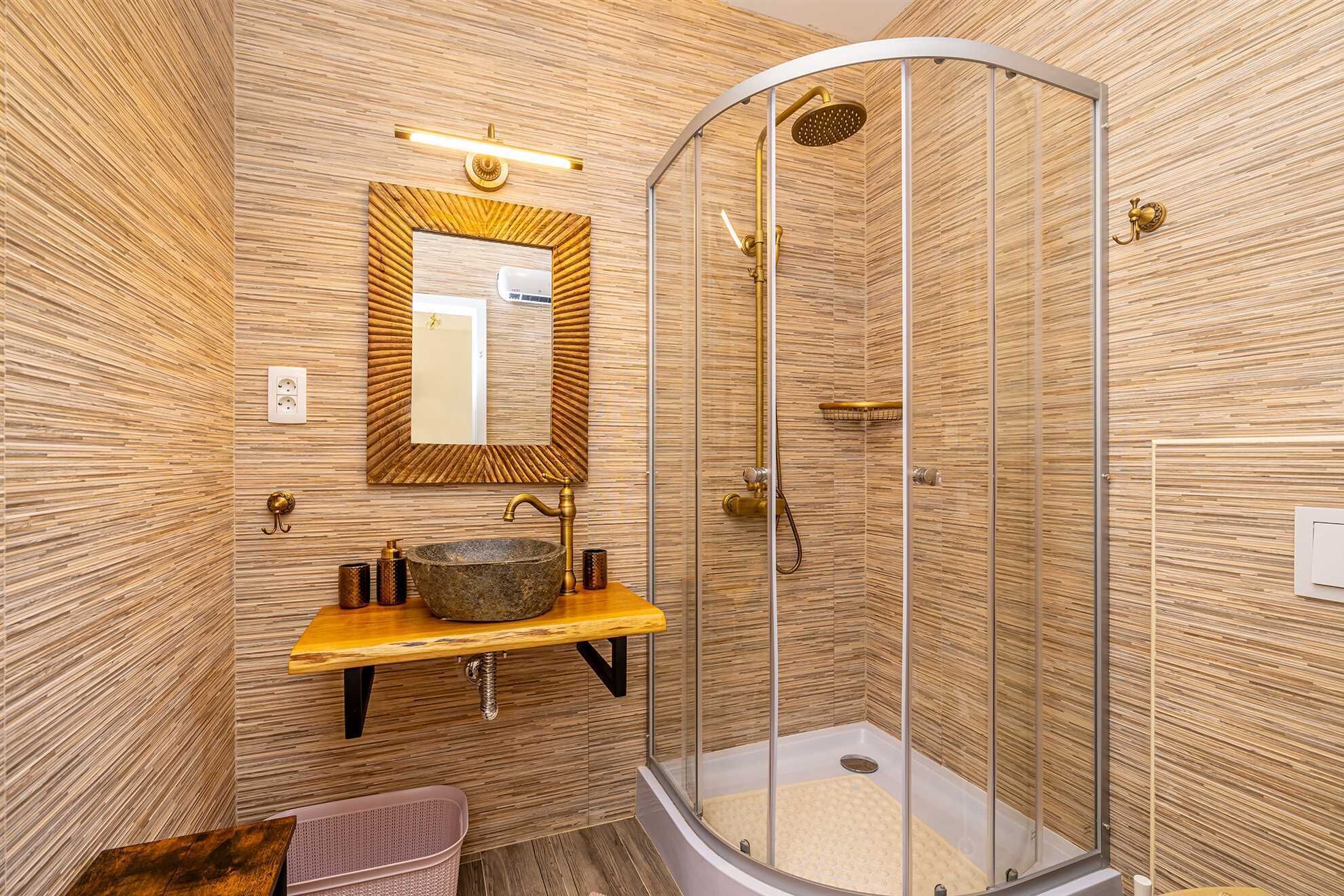 A modern bathroom with a wooden vanity, a large mirror, a shower enclosure, and a built-in sink.