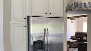 A stainless steel refrigerator with a water dispenser, white cabinetry, and a wooden countertop.