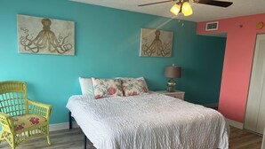 Ein Schlafzimmer mit einem Bett, einem Sessel und zwei Bildern an der Wand.