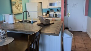Eine kleine Küche mit Spüle, Kühlschrank, Herd und Schränken.