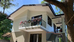 Une maison moderne à deux étages, dotée d’un balcon décoré de guirlandes festives.