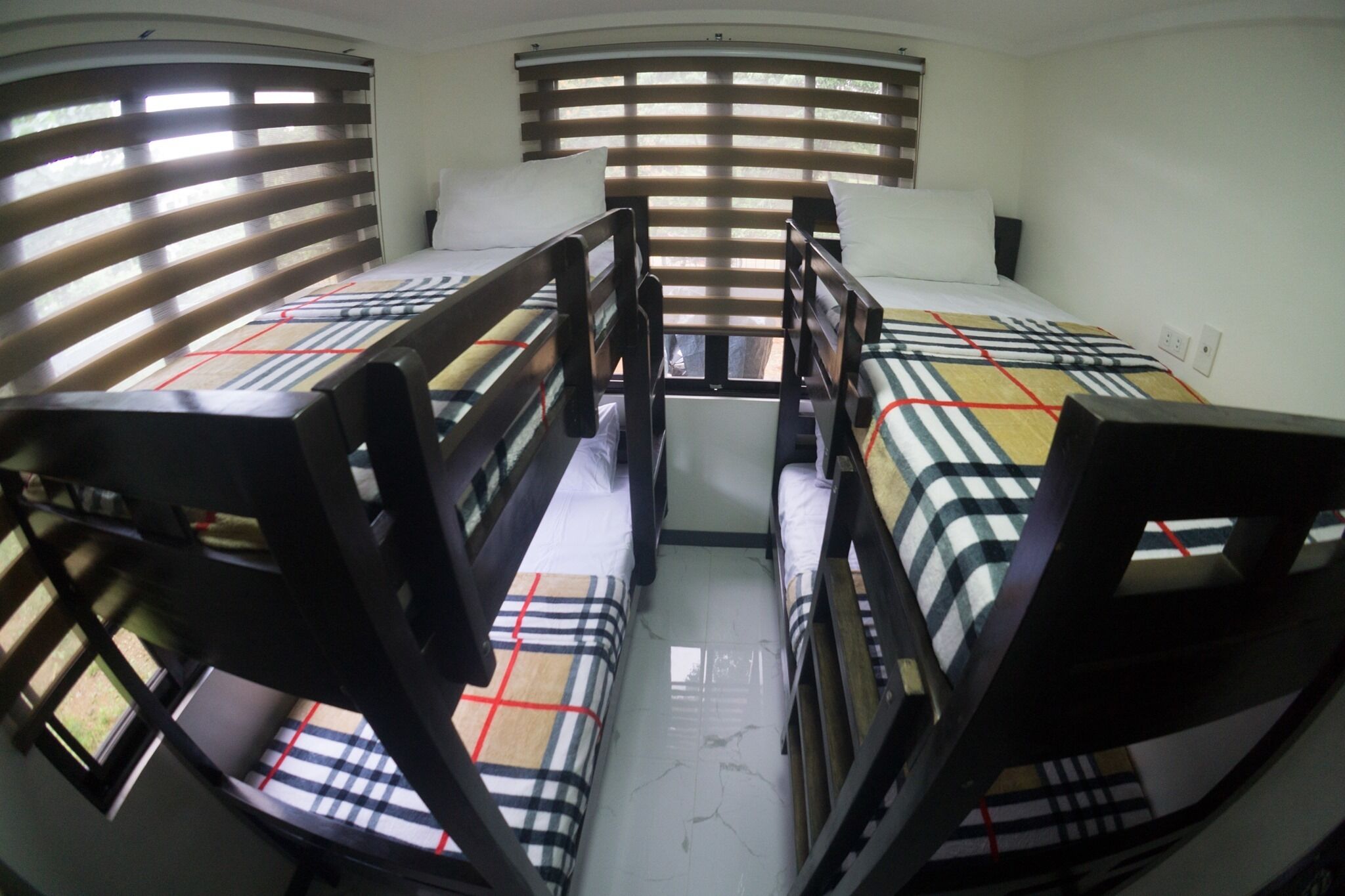 A compact room with bunk beds and a window with horizontal blinds.